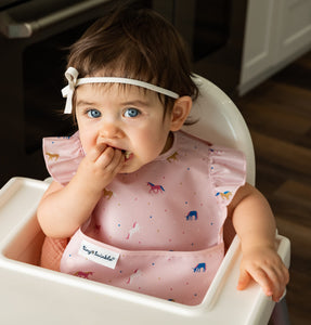 baby girl using the Tiny Twinkle's Easy Bib with Ruffles in Unicorn Confetti